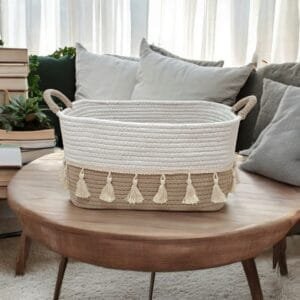 Hand-braided natural cotton rope Multipurpose shelf basket with decorative tassels, filled with folded blankets and plants, styled on a rustic wooden shelf for boho-chic home organization