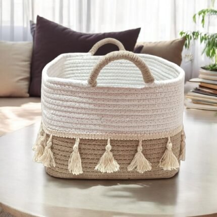 Hand-braided natural cotton rope shelf basket with decorative tassels, filled with folded blankets and plants, styled on a rustic wooden shelf for boho-chic home organization