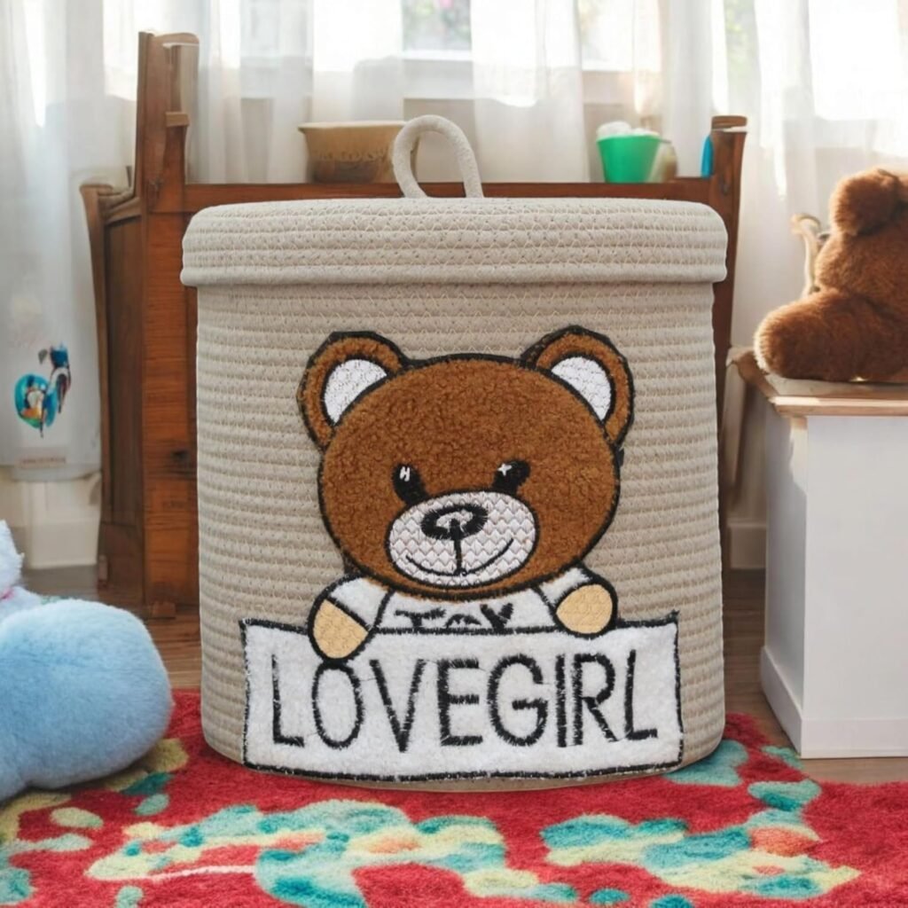 Beige cotton rope storage basket with embroidered teddy bear and Lovegirl A beautifully crafted beige cotton rope storage basket sits in a cozy nursery setting, showcasing its embroidered teddy bear motif and intricate Lovegirl Pattern. The removable lid is slightly open, revealing soft baby blankets inside, while the sturdy handles and natural texture of the eco-friendly cotton rope highlight its durability. The basket’s compact 10x10 inch size makes it ideal for shelves, corners, or as a decorative accent. Designed for safety and style, it blends seamlessly with neutral or pastel nursery themes. Pattern, removable lid, and handles – 10x10 inches (25x25 cm) nursery hamper
